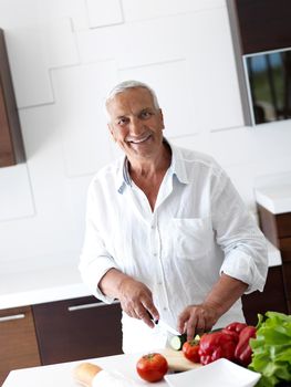 Handsome man cooking at home preparing salad in kitchen.