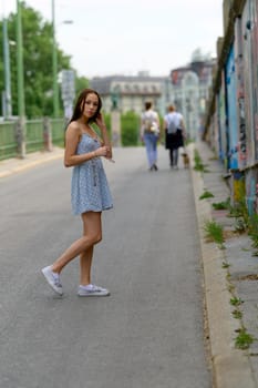 A portrait of a pretty young woman, taken in a city in the summer, is obviously waiting for her boyfriend.