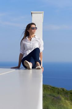 relaxed young beautiful woman in front of luxury modern home villa  on balcony on sunny day