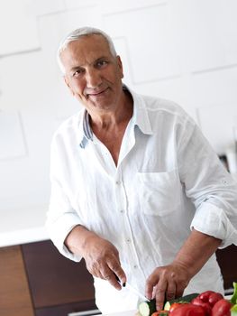 Handsome man cooking at home preparing salad in kitchen.