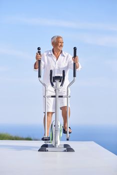 healthy senior man working out on gym treadmill machine at modern home terace with ocean view