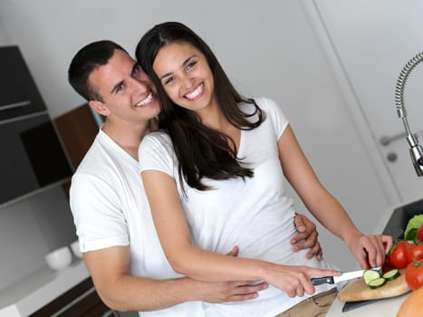 happy young couple have fun in modern kitchen indoor while preparing fresh fruits and vegetables food salad