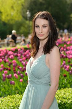 A beautiful young Russian woman in a park in the first warm spring sun with a light turquoise dress.