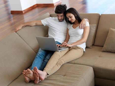 happy young relaxed  couple working on laptop computer at modern home indoor