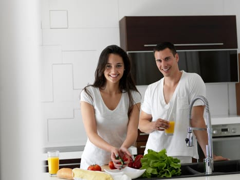 happy young couple have fun in modern kitchen indoor while preparing fresh fruits and vegetables food salad