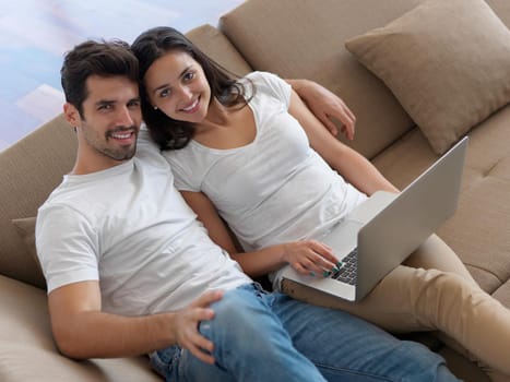 happy young relaxed  couple working on laptop computer at modern home indoor