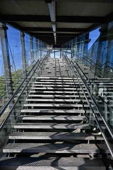 A modern light-flooded steel staircase protected from environmental influences by glass.