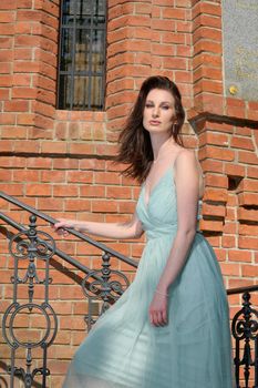 A beautiful young Russian woman in a park in the first warm spring sun with a light turquoise dress.