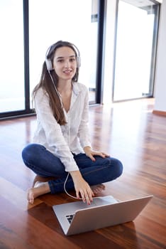 beautiful young woman relax and work on laptop computer modern  home office while listening musin on white headphones