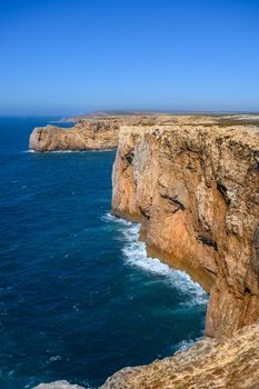 A beach with high rough cliffs at the Algarve in Portugal with some powerful waves.