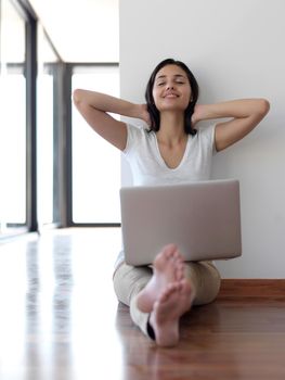 beautiful young woman relax and work on laptop computer modern  home office while listening musin on white headphones