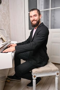 A young well dressed man is playing piano.