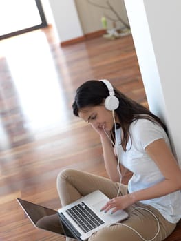 beautiful young woman relax and work on laptop computer modern  home office while listening musin on white headphones