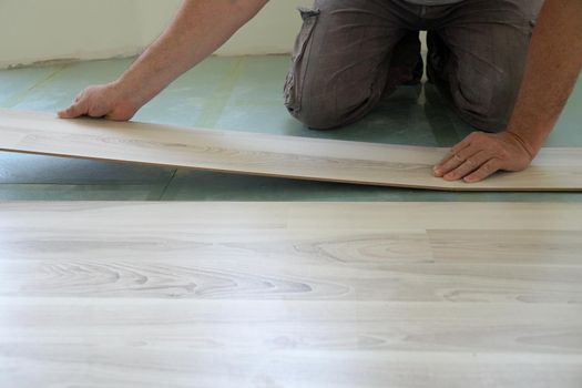 a worker assembles a laminate floor in a living room close-up