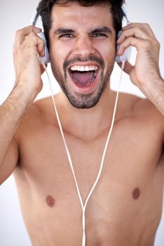 handsome young man listening music on headphones at modern home over  white wall and standing on hands