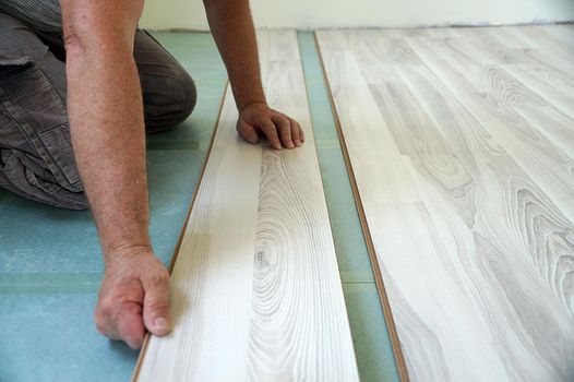 a worker assembles a laminate floor in a living room close-up