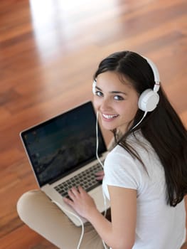 beautiful young woman relax and work on laptop computer modern  home office while listening musin on white headphones