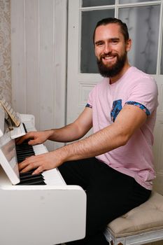 A young well dressed man is playing piano.