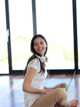 beautiful young woman relax and work on laptop computer modern  home office while listening musin on white headphones