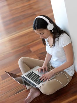 beautiful young woman relax and work on laptop computer modern  home office while listening musin on white headphones