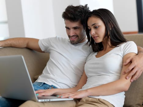 happy young relaxed  couple working on laptop computer at modern home indoor