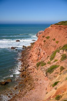 A view from over the cliff to the Atlantic Ocean and the waves crashing against the rocks in the Portuguese Algarve.