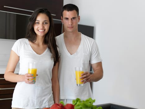 happy young couple have fun in modern kitchen indoor while preparing fresh fruits and vegetables food salad