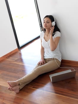 beautiful young woman relax and work on laptop computer modern  home office while listening musin on white headphones