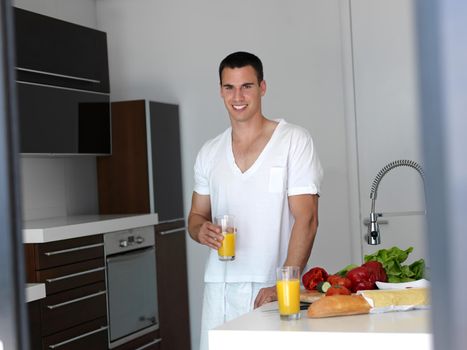 Handsome man cooking at home preparing salad in kitchen.