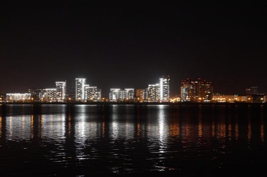 blurred photo, night city lights are reflected in the water, cityscape of Kazan