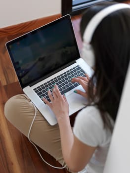 beautiful young woman relax and work on laptop computer modern  home office while listening musin on white headphones