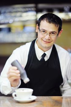 Barista prepares cappuccino in his coffee shop