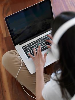 beautiful young woman relax and work on laptop computer modern  home office while listening musin on white headphones