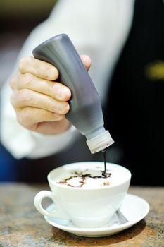 Barista prepares cappuccino in his coffee shop