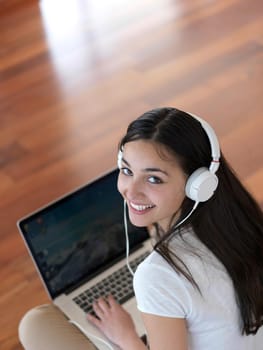 beautiful young woman relax and work on laptop computer modern  home office while listening musin on white headphones