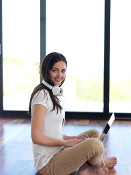 beautiful young woman relax and work on laptop computer modern  home office while listening musin on white headphones