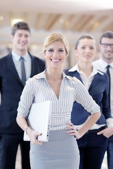 business woman standing with her staff in background at modern bright office conference room