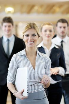 business woman standing with her staff in background at modern bright office conference room