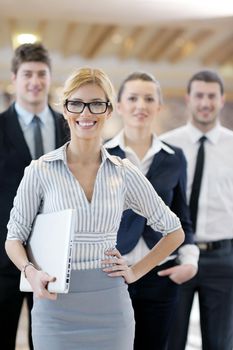 business woman standing with her staff in background at modern bright office conference room