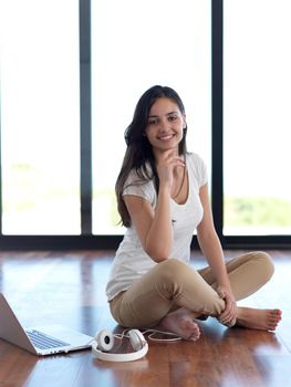 beautiful young woman relax and work on laptop computer modern  home office while listening musin on white headphones