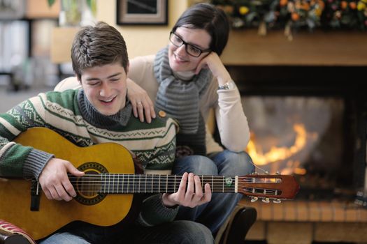 happy Young romantic couple sitting on sofa in front of fireplace at winter season in home