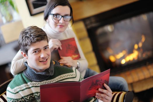 happy Young romantic couple sitting on sofa in front of fireplace at winter season in home