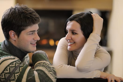 happy Young romantic couple sitting on sofa in front of fireplace at winter season in home