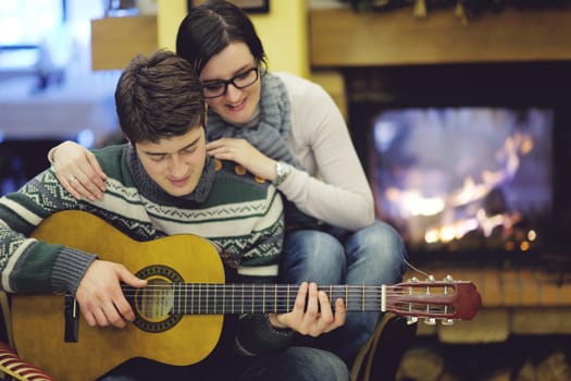 happy Young romantic couple and relaxing sofa in front of fireplace at winter season in home