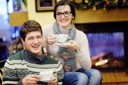 happy Young romantic couple sitting on sofa in front of fireplace at winter season in home