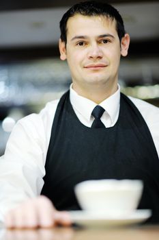 Barista prepares cappuccino in his coffee shop
