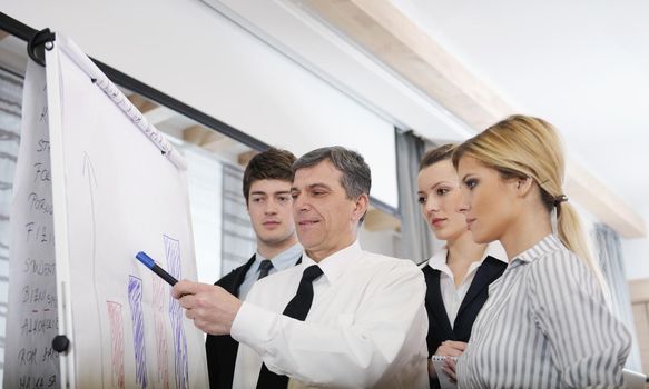 Senior male business man giving a presentation at a  meeting at modern light office on a table board