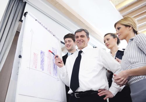 Senior male business man giving a presentation at a  meeting at modern light office on a table board