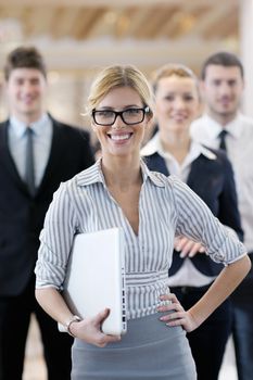 business woman standing with her staff in background at modern bright office conference room