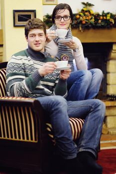 happy Young romantic couple sitting on sofa in front of fireplace at winter season in home